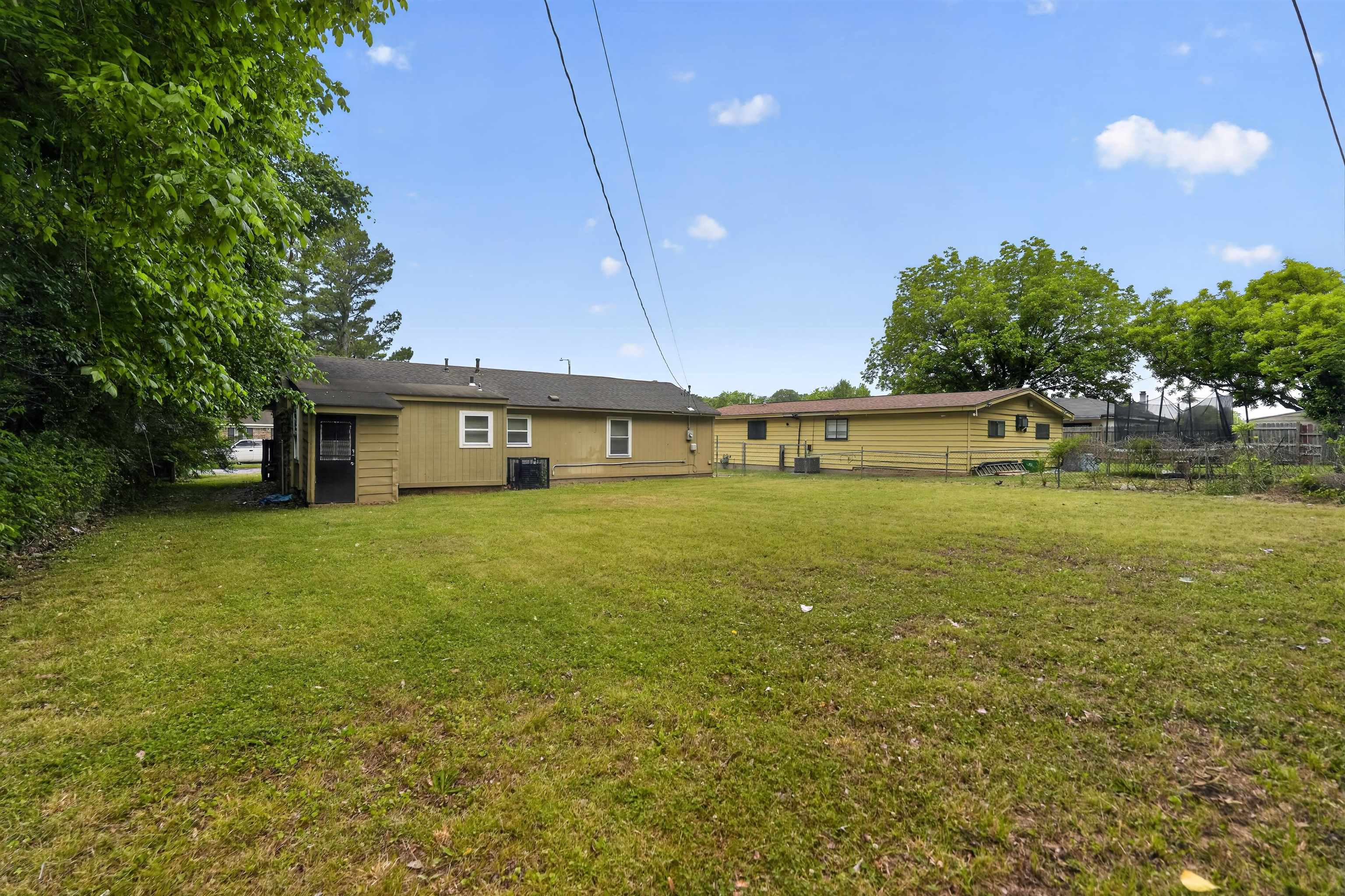 3608 Cane Ridge Drive Memphis, TN 38109 - Photo 2 of 31 Expansive green space featuring a large lawn, mature trees, and a single-story residence with light-colored siding and a screened-in porch