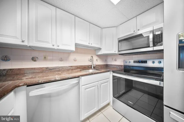 a kitchen with granite countertop white cabinets and stainless steel appliances