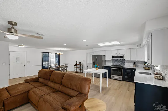 a living room with stainless steel appliances kitchen island granite countertop a couch a stove a dining table and chairs