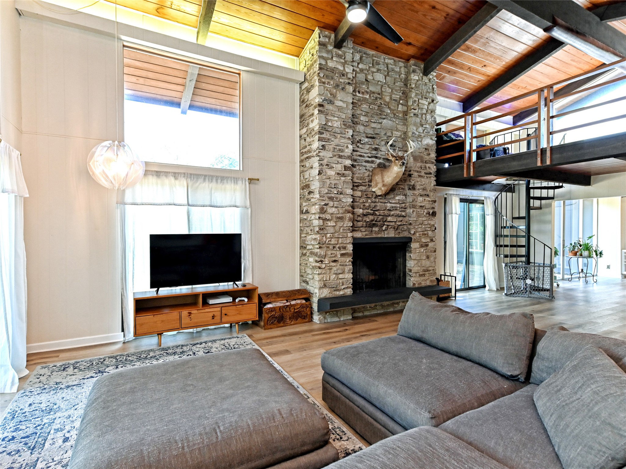 115 Snapper Street Lakeway, TX 78734 - Photo 6 of 30 A grand stone fireplace anchors this living space, featuring high ceilings and an elegant spiral staircase leading to an upper loft.