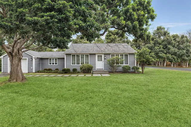 a front view of a house with a garden and trees