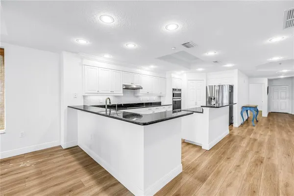 a kitchen with stainless steel appliances granite countertop a sink and a refrigerator