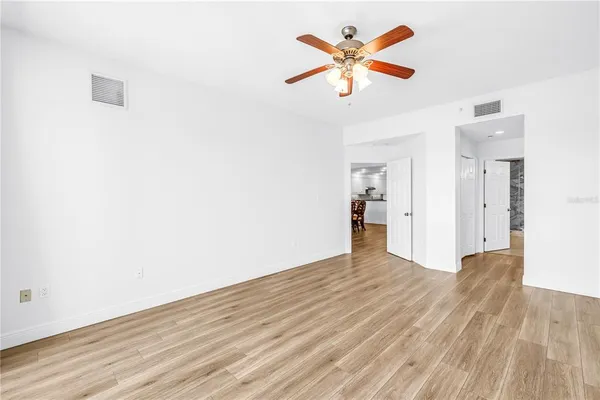 an empty room with wooden floor and a ceiling fan
