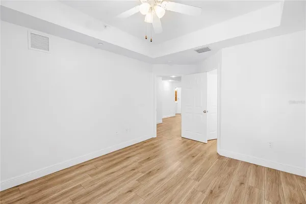 a view of empty room with wooden floor and fan