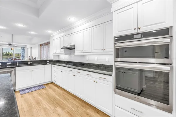 a kitchen with granite countertop white cabinets stainless steel appliances and sink