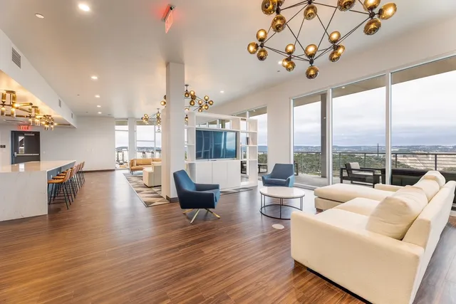 a living room with furniture large window and wooden floor