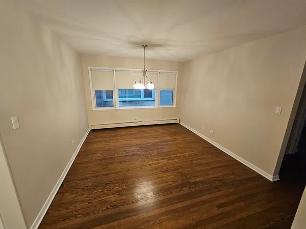 an empty room with wooden floor and chandelier