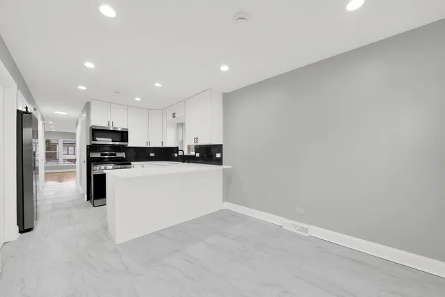 a view of kitchen with refrigerator sink and white cabinets