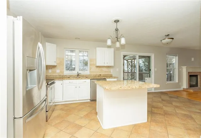 a large kitchen with kitchen island a chandelier stainless steel appliances cabinets and a counter top space