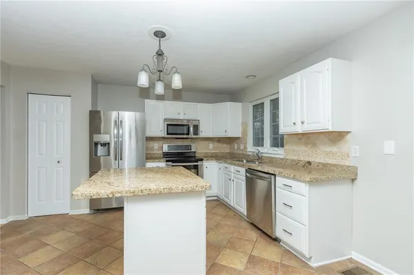 a kitchen with stainless steel appliances granite countertop a sink dishwasher stove top oven and refrigerator