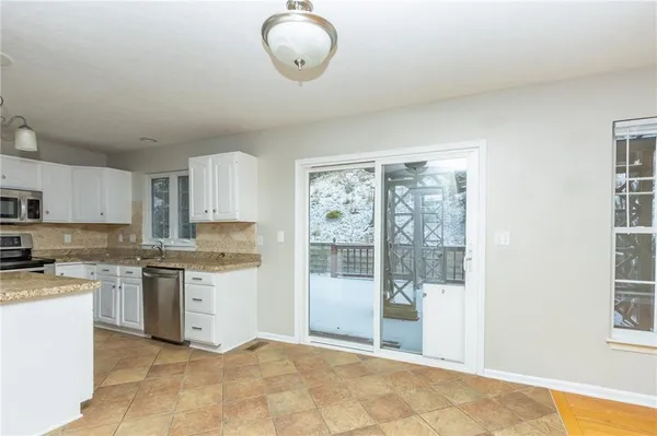 a kitchen with stainless steel appliances granite countertop a stove top oven a sink dishwasher and white cabinets with wooden floor