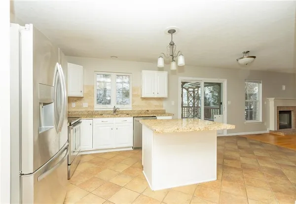 a large kitchen with kitchen island a chandelier stainless steel appliances cabinets and a counter top space