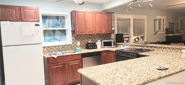 a kitchen with stainless steel appliances kitchen island granite countertop a refrigerator a sink dishwasher and white cabinets with wooden floor