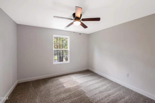 an empty room with a ceiling fan and a window