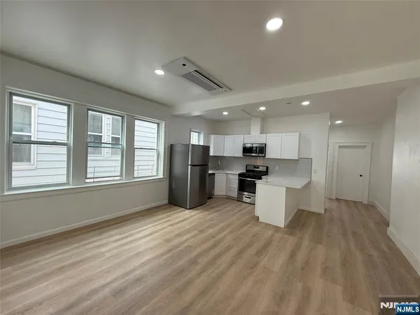 a large kitchen with kitchen island white cabinets and stainless steel appliances
