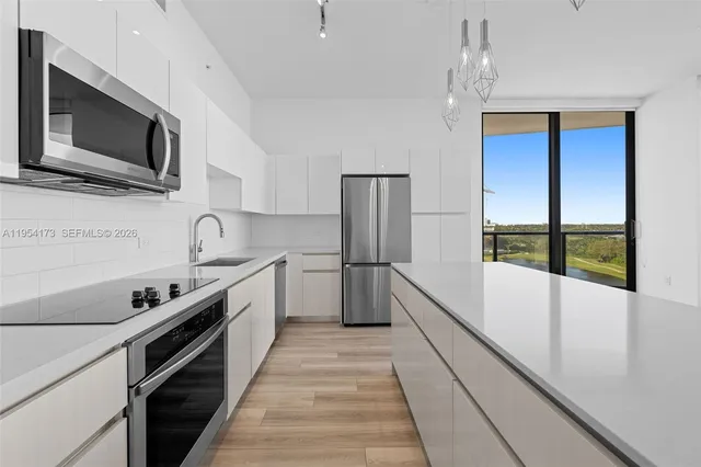 a view of a kitchen with kitchen island a sink wooden floor and a large window
