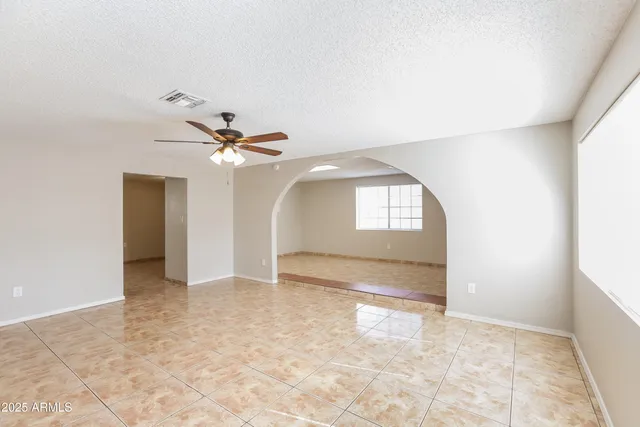 an empty room with a ceiling fan and a window