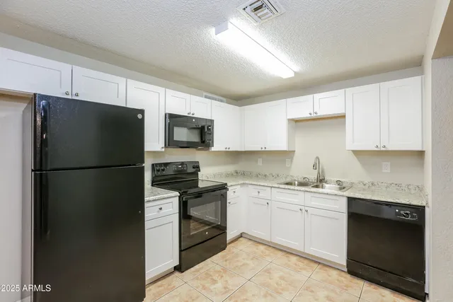 a kitchen with a sink a refrigerator and white cabinets