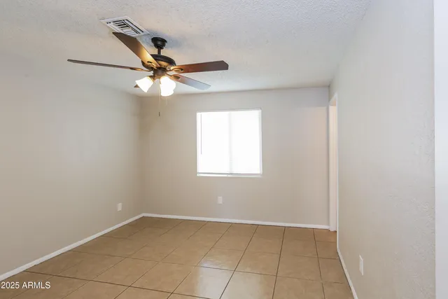 an empty room with a window and a fan