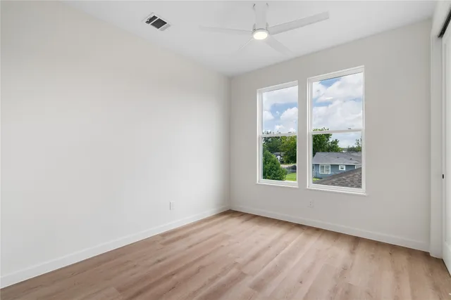 an empty room with wooden floor and windows