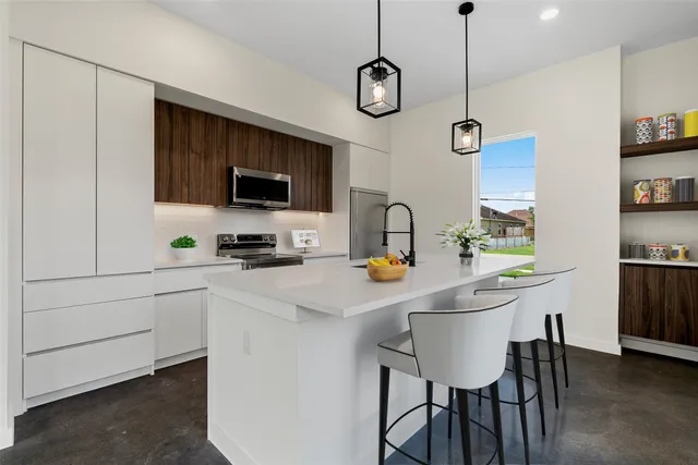 a kitchen with stainless steel appliances a stove a sink and chairs