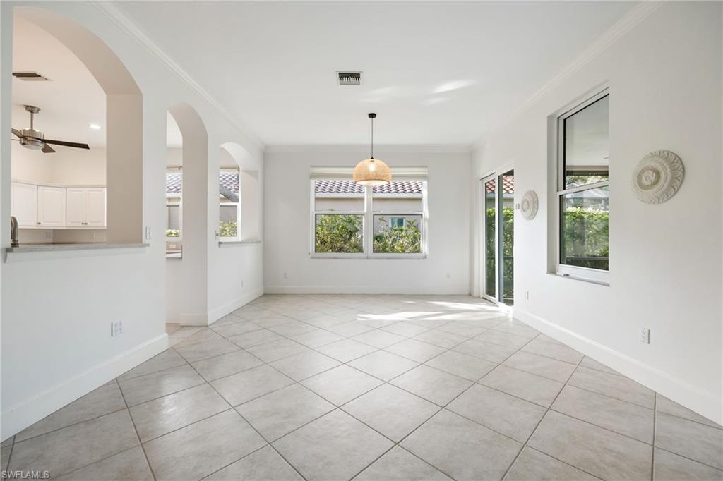982 Fountain Run Naples, FL 34119 - Photo 13 of 44 Unfurnished dining area featuring crown molding, light tile patterned floors, a ceiling fan, and arched walkways
