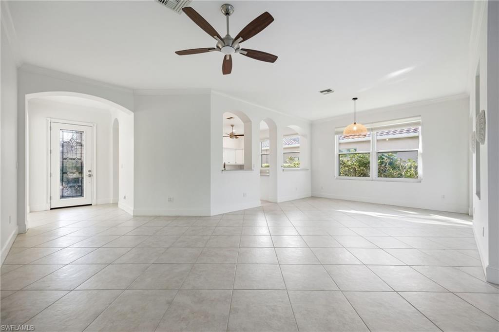 982 Fountain Run Naples, FL 34119 - Photo 14 of 44 Unfurnished room featuring arched walkways, ornamental molding, ceiling fan, light tile patterned floors, and healthy amount of natural light