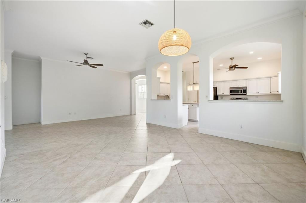982 Fountain Run Naples, FL 34119 - Photo 15 of 44 Unfurnished living room featuring ceiling fan, arched walkways, ornamental molding, light tile patterned floors, and recessed lighting
