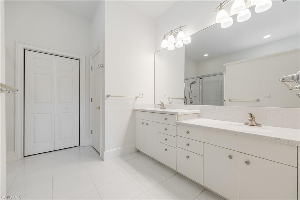 982 Fountain Run Naples, FL 34119 - Photo 23 of 44 Full bathroom featuring double vanity, a closet, a stall shower, and light tile patterned floors