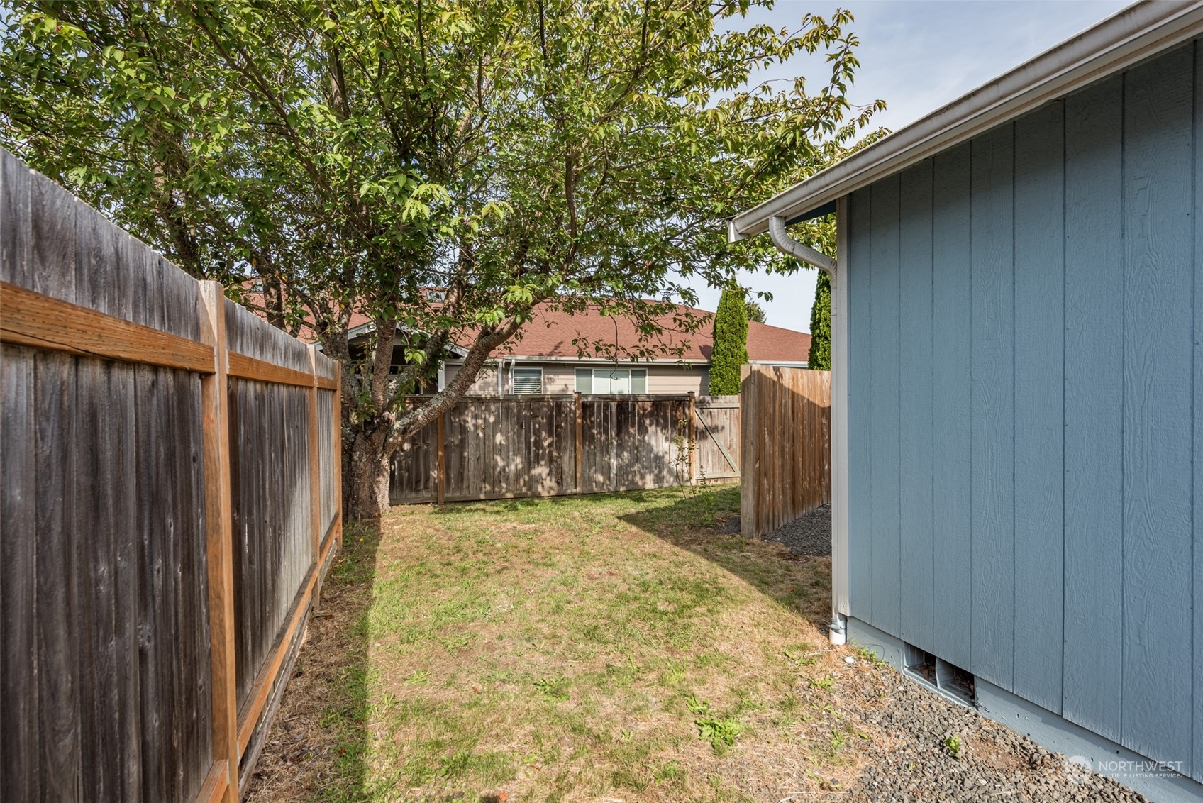 818 East Washington Place Sequim, WA 98382 - Photo 26 of 28 a view of a yard with wooden fence and a large tree