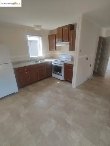 a large white kitchen with cabinets a sink a window and a counter top space