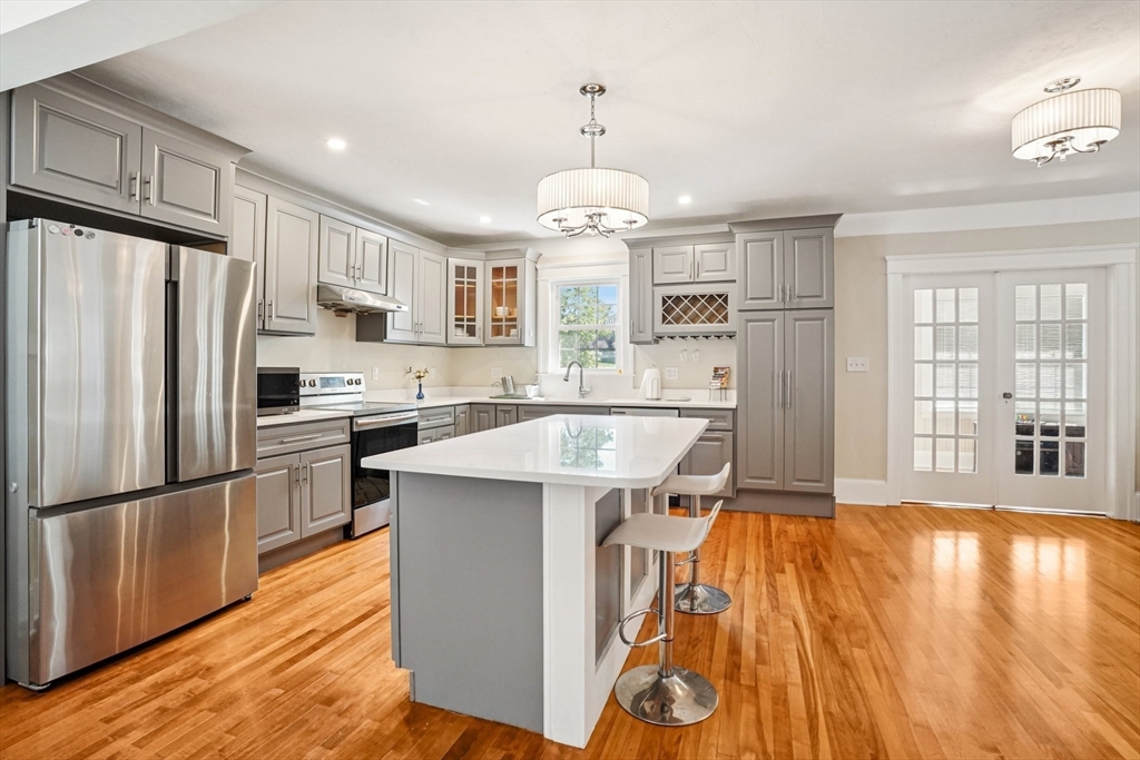 174 Park Avenue, Unit 1 Worcester, MA 01602 - Photo 8 of 34 a large kitchen with stainless steel appliances kitchen island granite countertop a refrigerator a stove a sink dishwasher and white cabinets with wooden floor