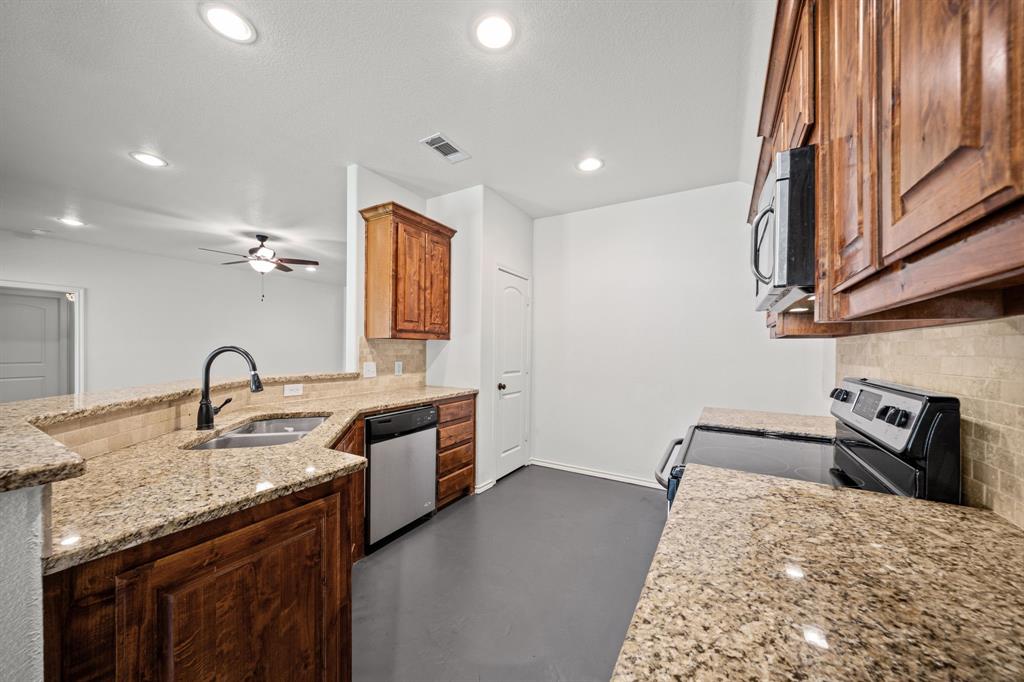 229 Firefly Drive Springtown, TX 76082 - Photo 8 of 33 Kitchen with light-toned granite countertops, a stainless steel sink, and dark wood cabinetry