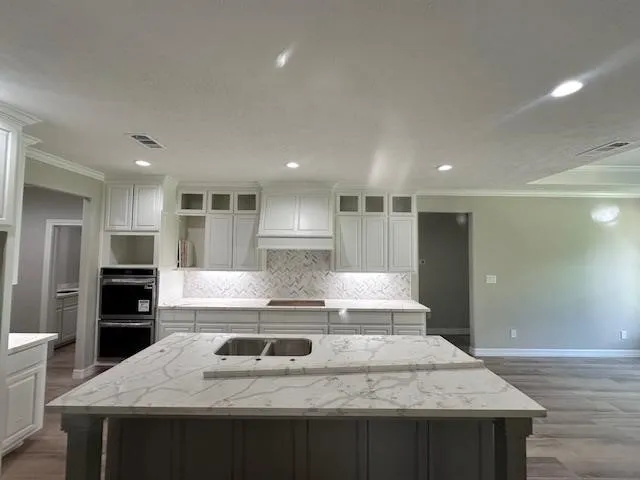 a large kitchen with kitchen island a stove a sink dishwasher and a refrigerator with wooden floor