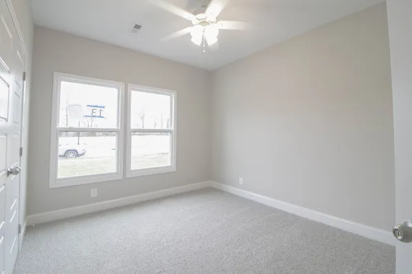 an empty room with a window and a fan