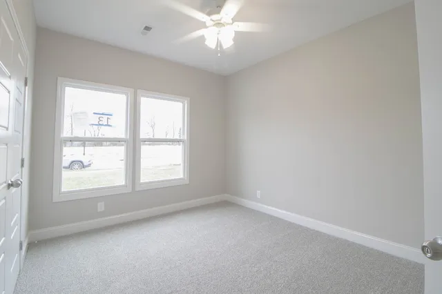 an empty room with a window and a fan