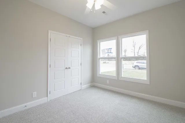 an empty room with a window and a chandelier fan
