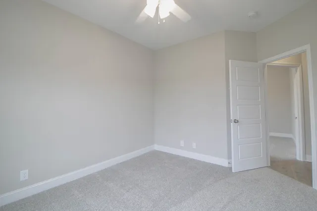 an empty room with a ceiling fan and a window