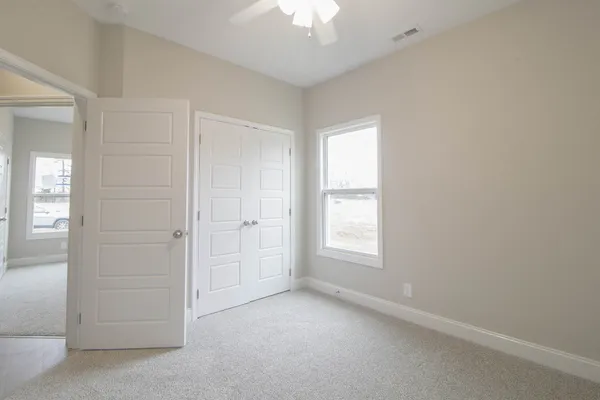 an empty room with chandelier fan and windows