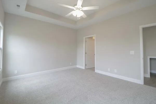 a view of an empty room and chandelier fan