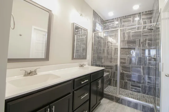 a bathroom with a shower sink vanity and mirror