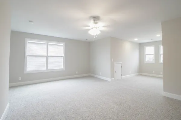 an empty room with windows and chandelier fan