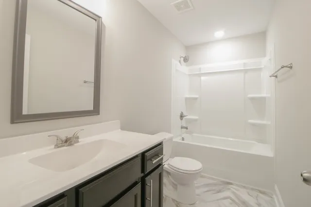 a bathroom with a granite countertop sink toilet a mirror and shower