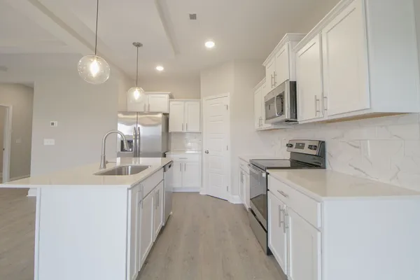 a kitchen with kitchen island a sink appliances cabinets and a counter top space
