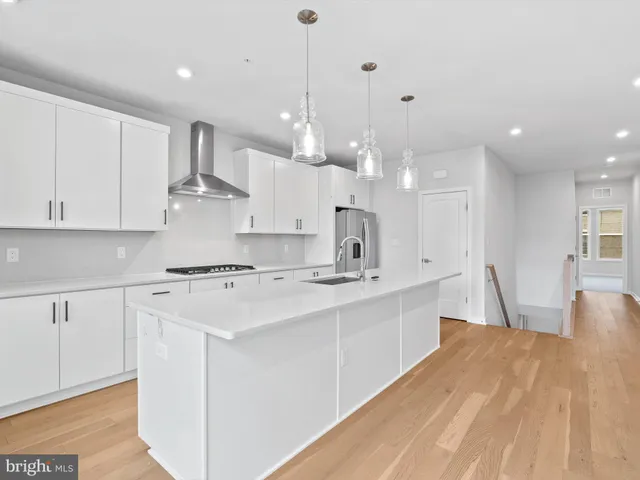 a large kitchen with stainless steel appliances lots of white cabinets