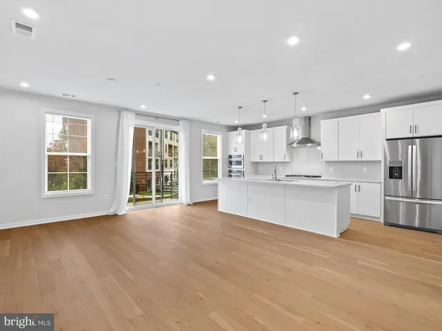 a large kitchen with stainless steel appliances granite countertop a large counter top a refrigerator and cabinets