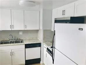 a kitchen with a refrigerator and white cabinets