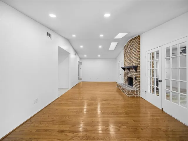 an empty room with wooden floor and a fireplace