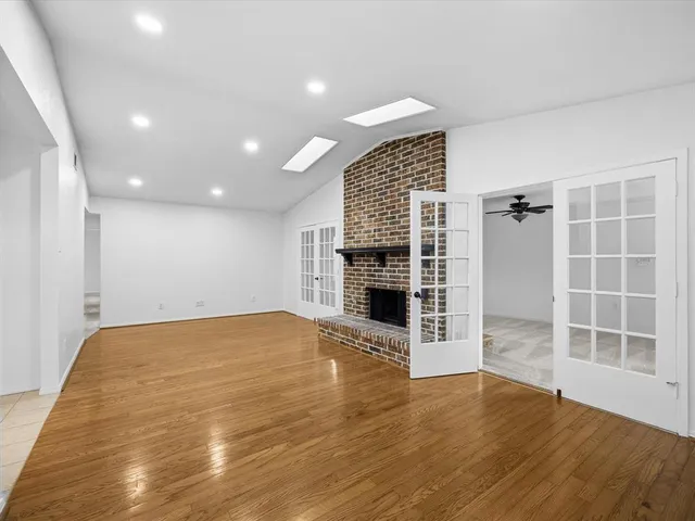 a view of an empty room with wooden floor and a fireplace