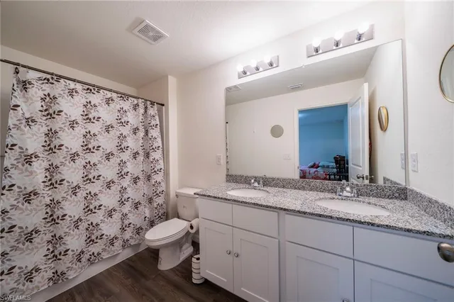 a bathroom with a granite countertop sink mirror vanity and toilet